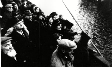 Closeup of a crowd of women and men in hats on a ship, with a child holding on to a rope near the side